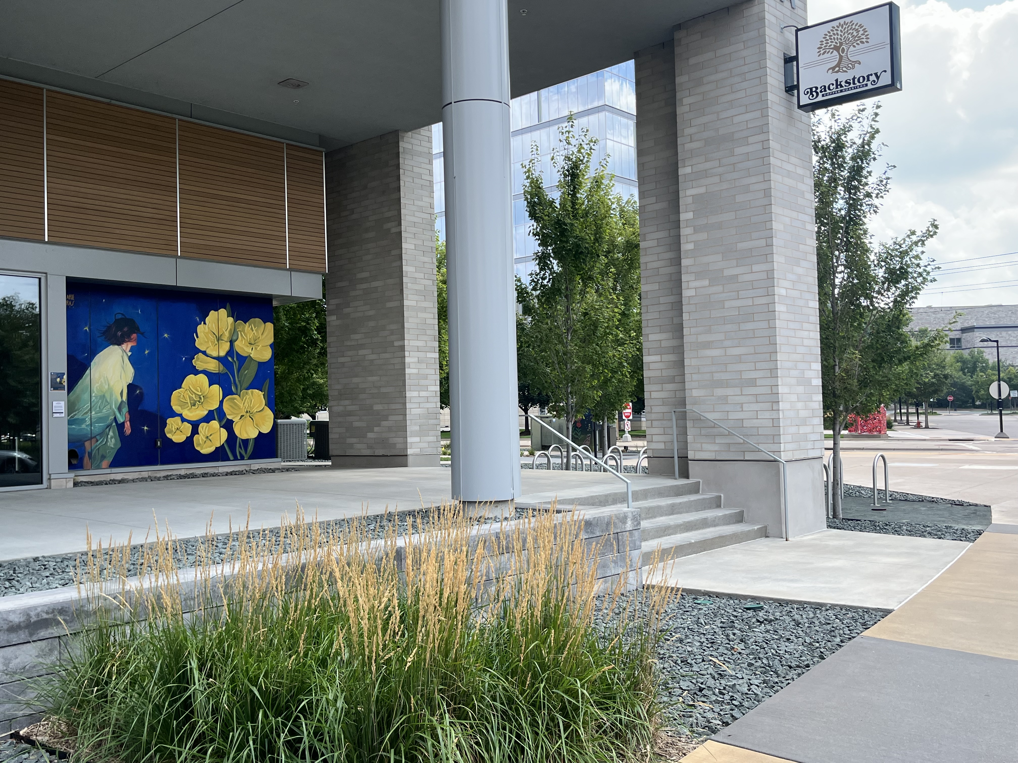 A mural depicts flowers and a woman on a deep blue night sky, located on a coffee shop's exterior wall.
